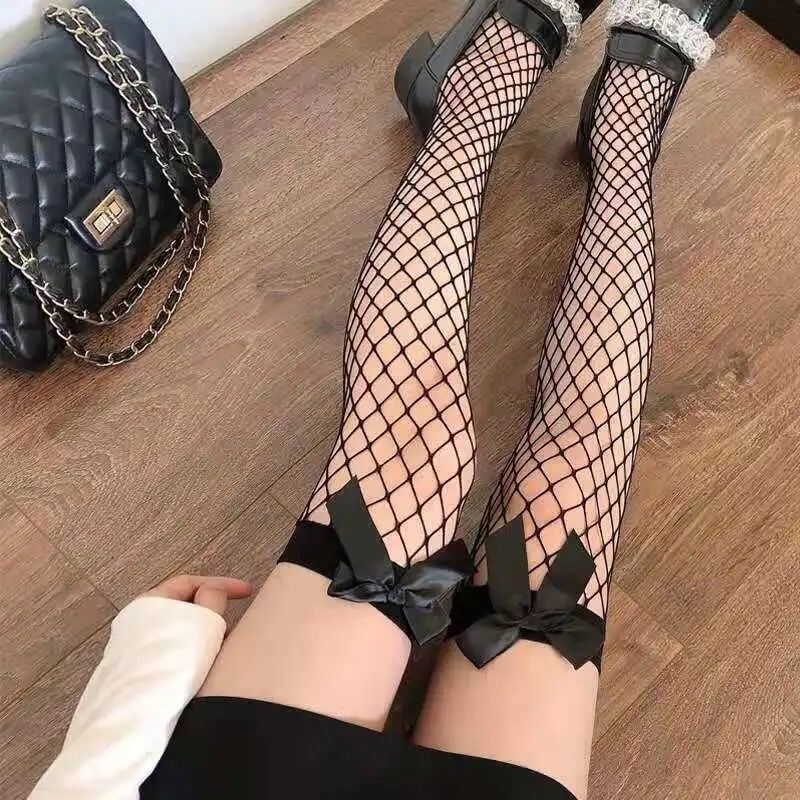 Femboy in black fishnet thigh high stockings with bow