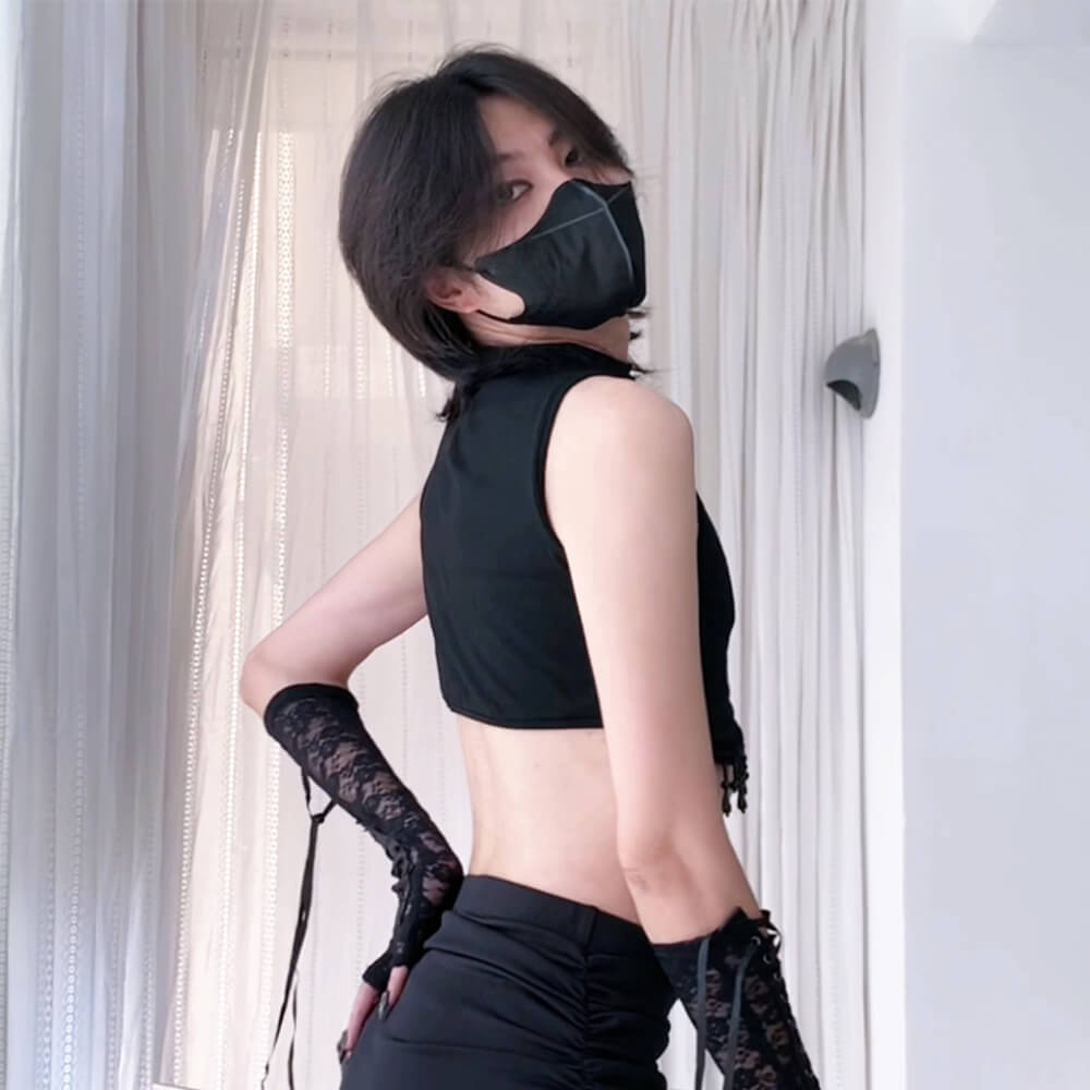 Person wearing a black sleeveless top, black pants, and black gloves with lace cuffs.