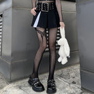 Femboy in black skirt and top with black fishnet pantyhose with butterfly