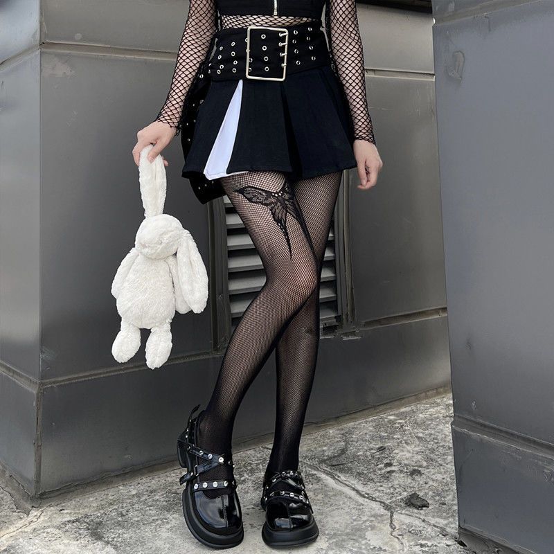 Femboy in black skirt and top with fishnet pantyhose with butterfly