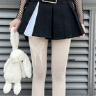 Femboy in black skirt and top with white fishnet pantyhose with butterfly and rabbit plush