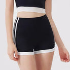 Black athletic shorts with white side stripes and a white hem, shown on a model against a light gray background.
