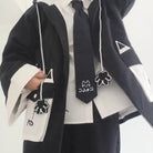 Person wearing a black and white outfit with a tie and accessories on a white background