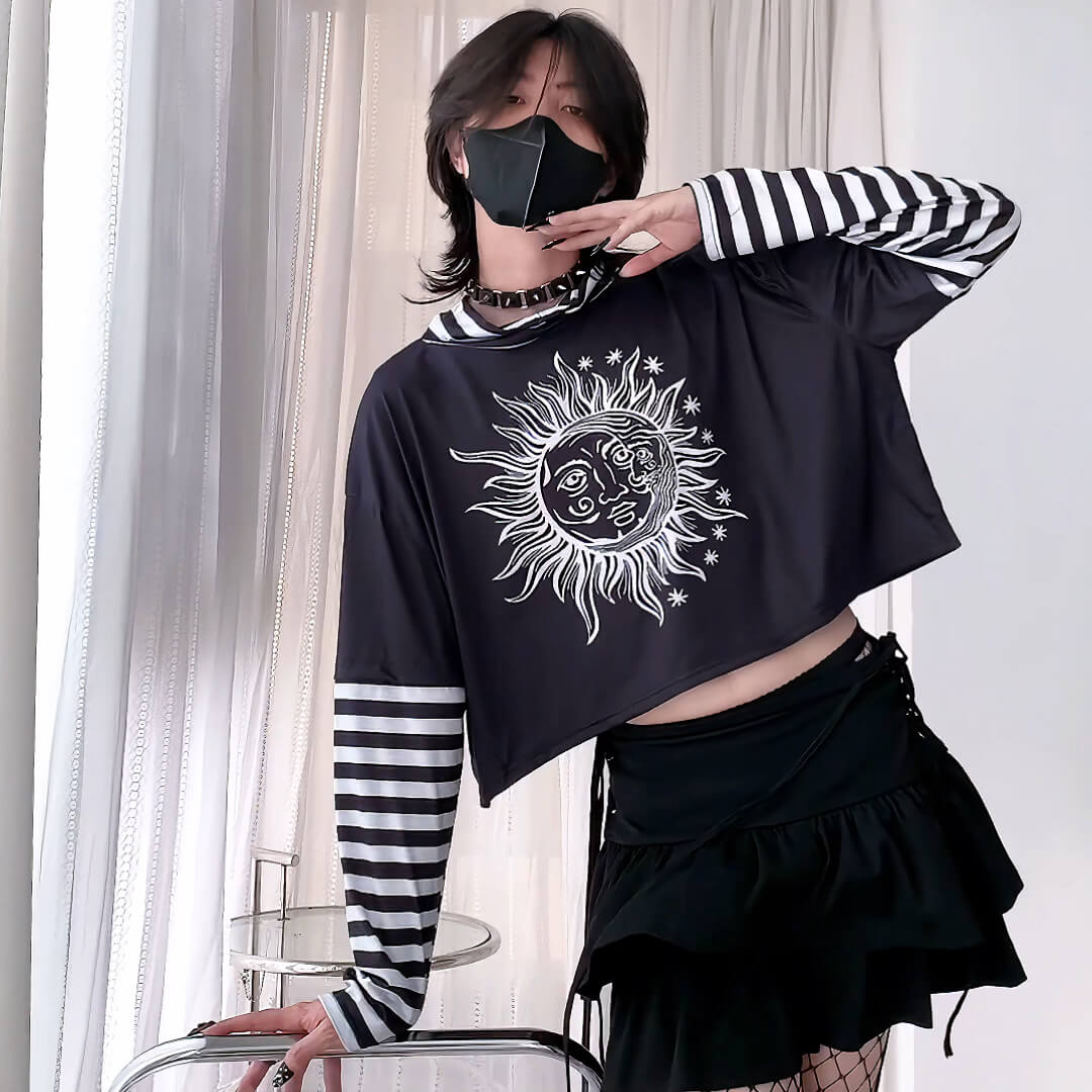 Person wearing a black crop top with a sun and moon design and a black skirt.