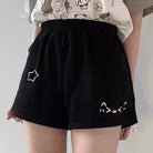 Black shorts with white cat designs worn by a femboy a plain background