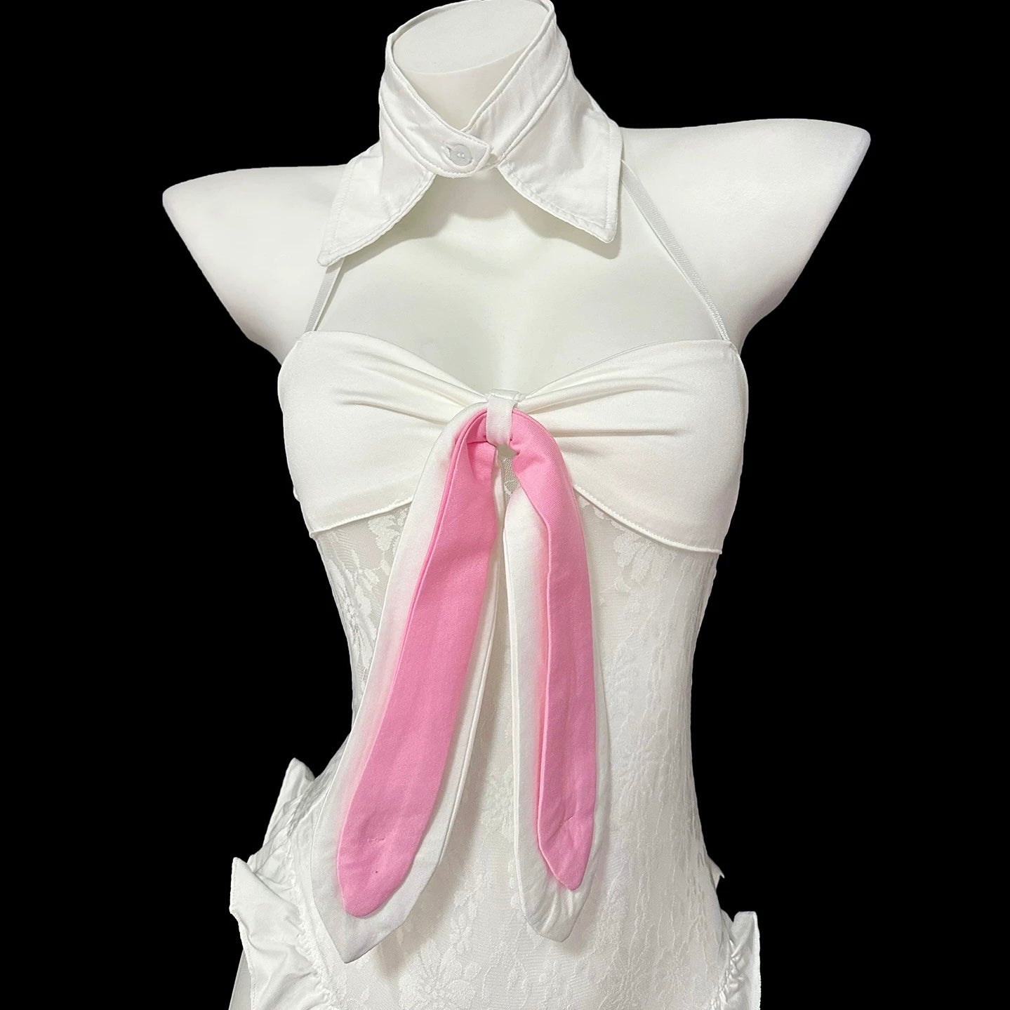 Person wearing a black and white bunny costume with fishnet stockings, sitting on a white chair.