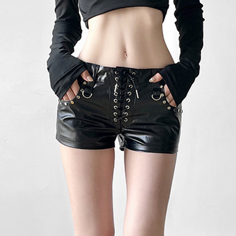 Black leather shorts with lace-up front and studded details on a plain background