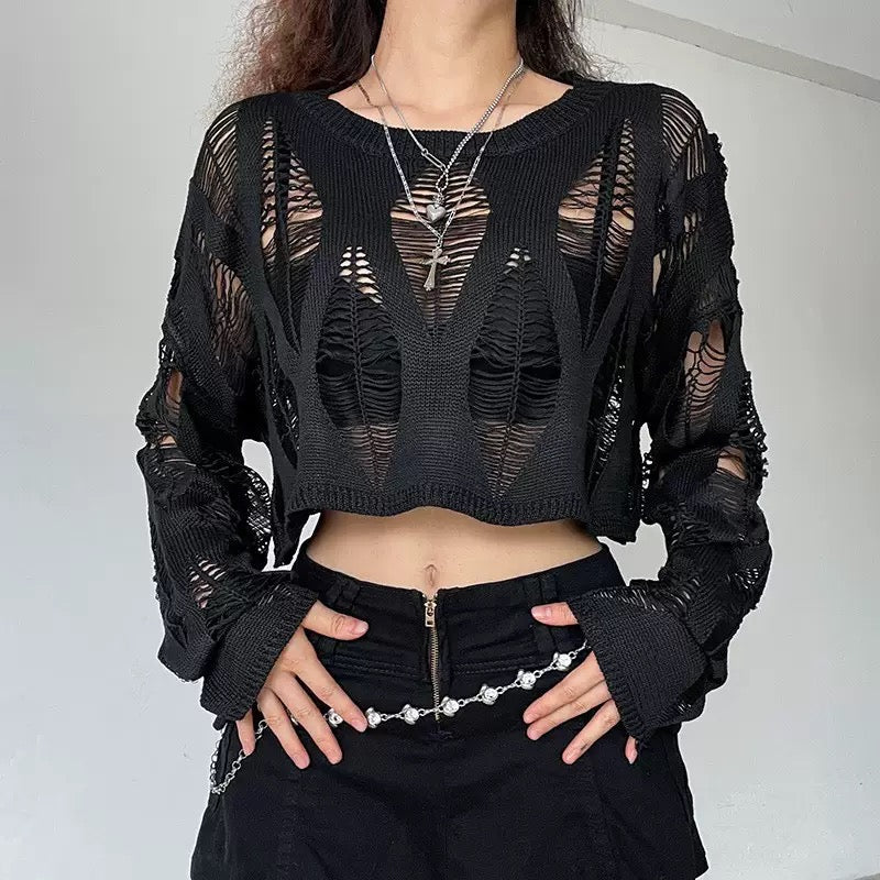 Person wearing a black, sheer knit top with a plain background