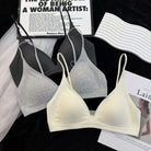 Three wireless triangle bralettes in light gray, medium gray, and cream are arranged in a flat-lay with styling props including a wavy white strap, a magazine page, and a black fabric background.