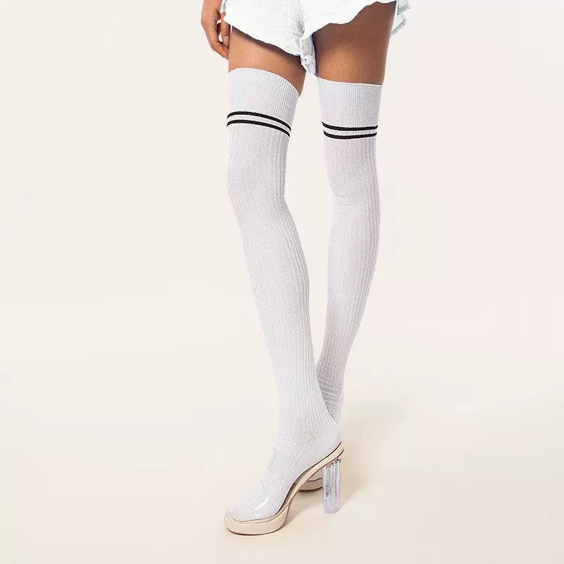 White thigh-high socks with black stripes worn by a person on a light beige background