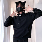 Femboy wearing a black hoodie with cat ears and a matching mask, posing against a neutral background.