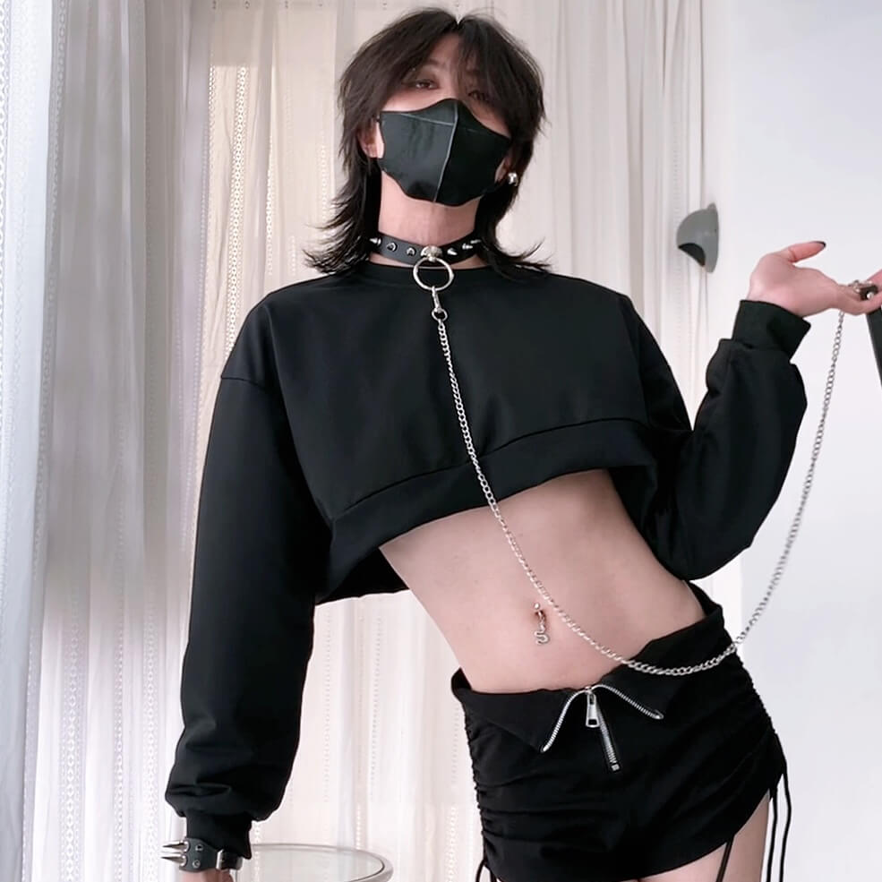 Person wearing a black outfit with a choker and mask, holding a chain.