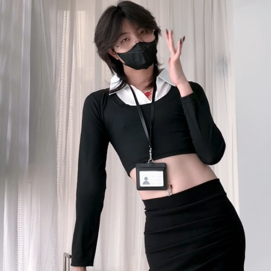 Femboy wearing a black outfit with a white shirt underneath, standing against a neutral background.