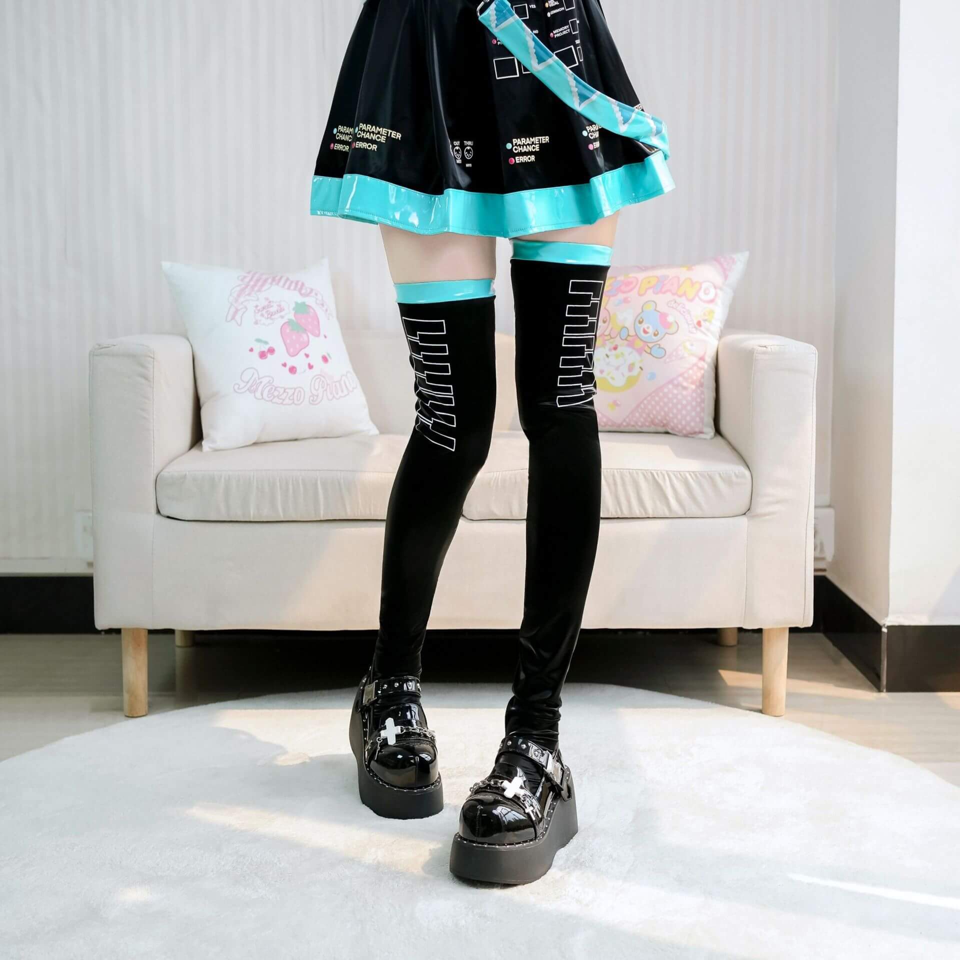 Person wearing black knee-high socks with white text, black shoes, and a black dress with blue trim in a room.