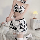 Person wearing a cow print outfit with a skirt and top, sitting on a bed.