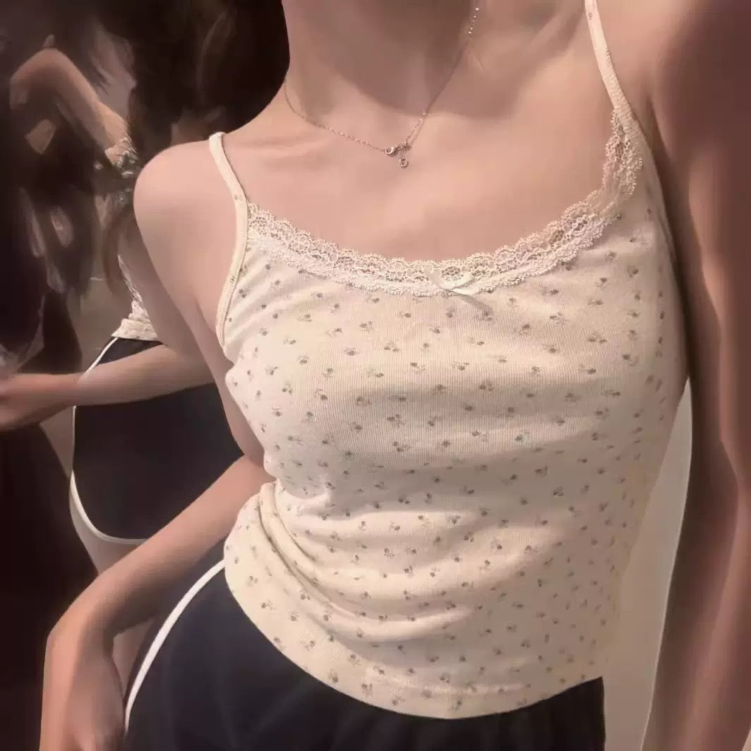 Close-up of a femboy wearing a white sweet camisole top with a blurred background
