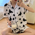 Femboy wear a white and black cow print short sleeve top and shorts pajama set