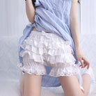 Person wearing a light blue shirt and white ruffled shorts on a white background