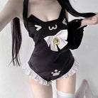 A femboy wearing a black cat-themed one-piece swimsuit or costume with white ruffled trim, a large white bow with a gold bell, and white cat face and paw print graphics, photographed against a plain light background.