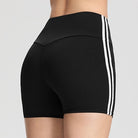 Femboy wearing black athletic shorts on a plain background