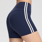 Femboy wearing black and red athletic shorts on a plain background