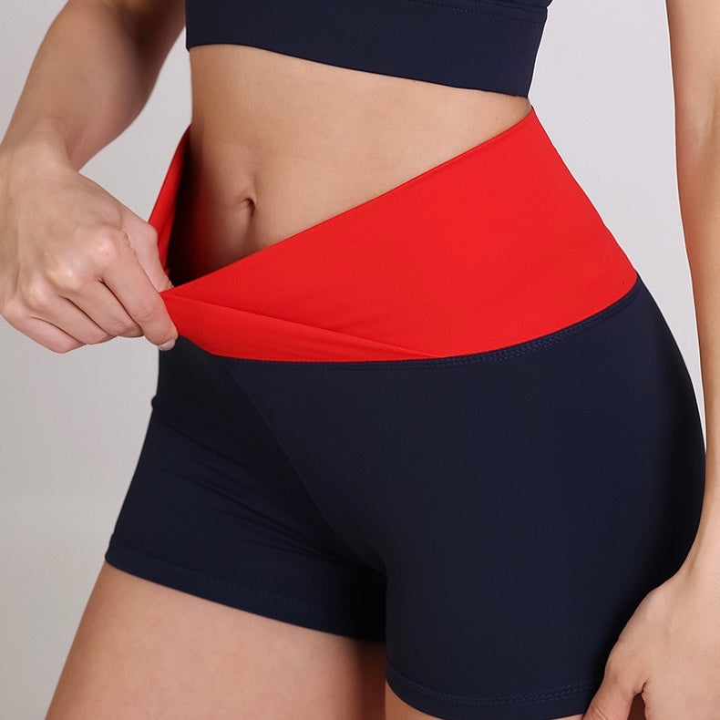 Femboy wearing black and red athletic shorts on a plain background