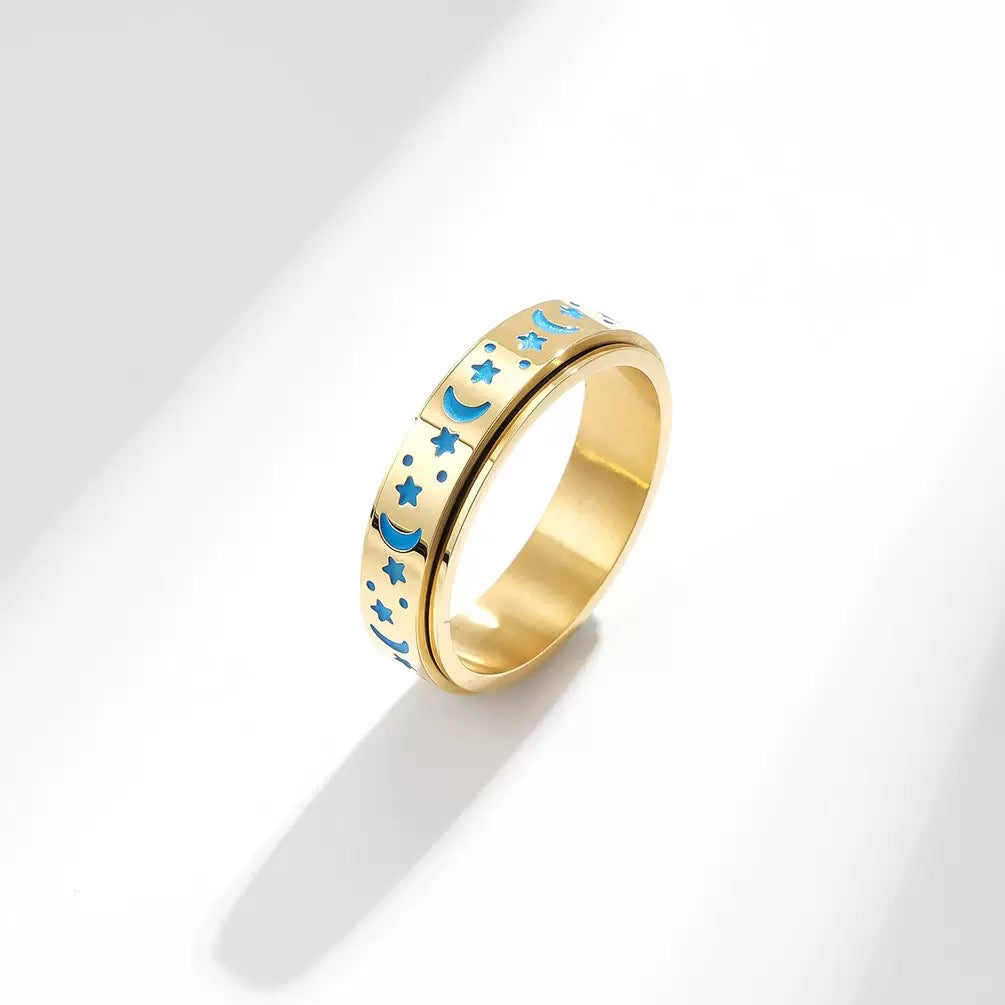 Gold ring with blue star and moon designs on a white background