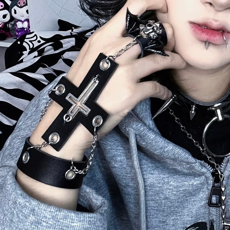 Person wearing a black gothic cross skull ring chain bracelet details.