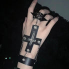 Hand wearing a black gothic cross skull ring chain bracelet details against a dark background