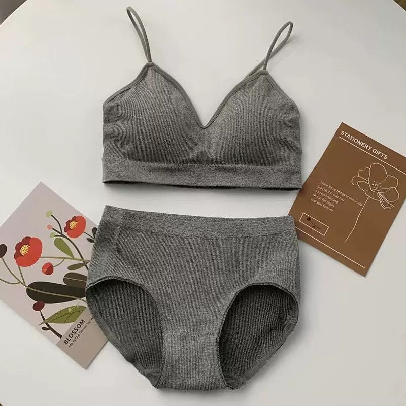 A two-piece gray ribbed knit underwear set consisting of a camisole-style bra top and matching high-cut briefs, arranged on a white surface with decorative printed cards.
