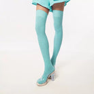 Green thigh-high socks with clear high heels on a white background