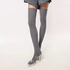 Gray thigh-high socks worn with a skirt on a white background