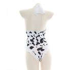White and black halter cow print bodysuit lingerie on a mannequin against a white background
