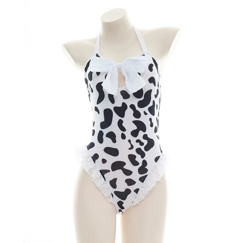 Black and white halter cow print bodysuit lingerie with bow detail on a mannequin against a white background