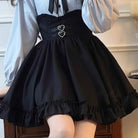 Person wearing a black pinafore dress with heart details over a light blue shirt.