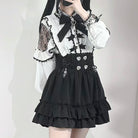 Person wearing a black and white outfit with lace details on a plain background