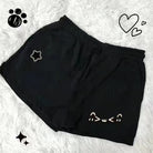 Black shorts with white designs on a textured white background