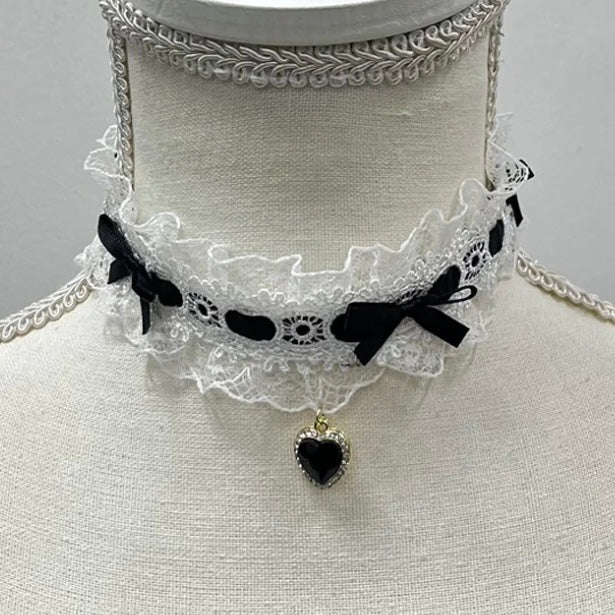 Lace choker with black bows and a heart-shaped pendant on a white background