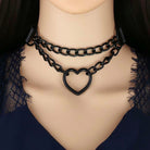 Black chain choker with heart design on a mannequin neck against a dark background