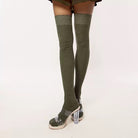 Olive green thigh-high socks with clear high-heeled shoes on a white background