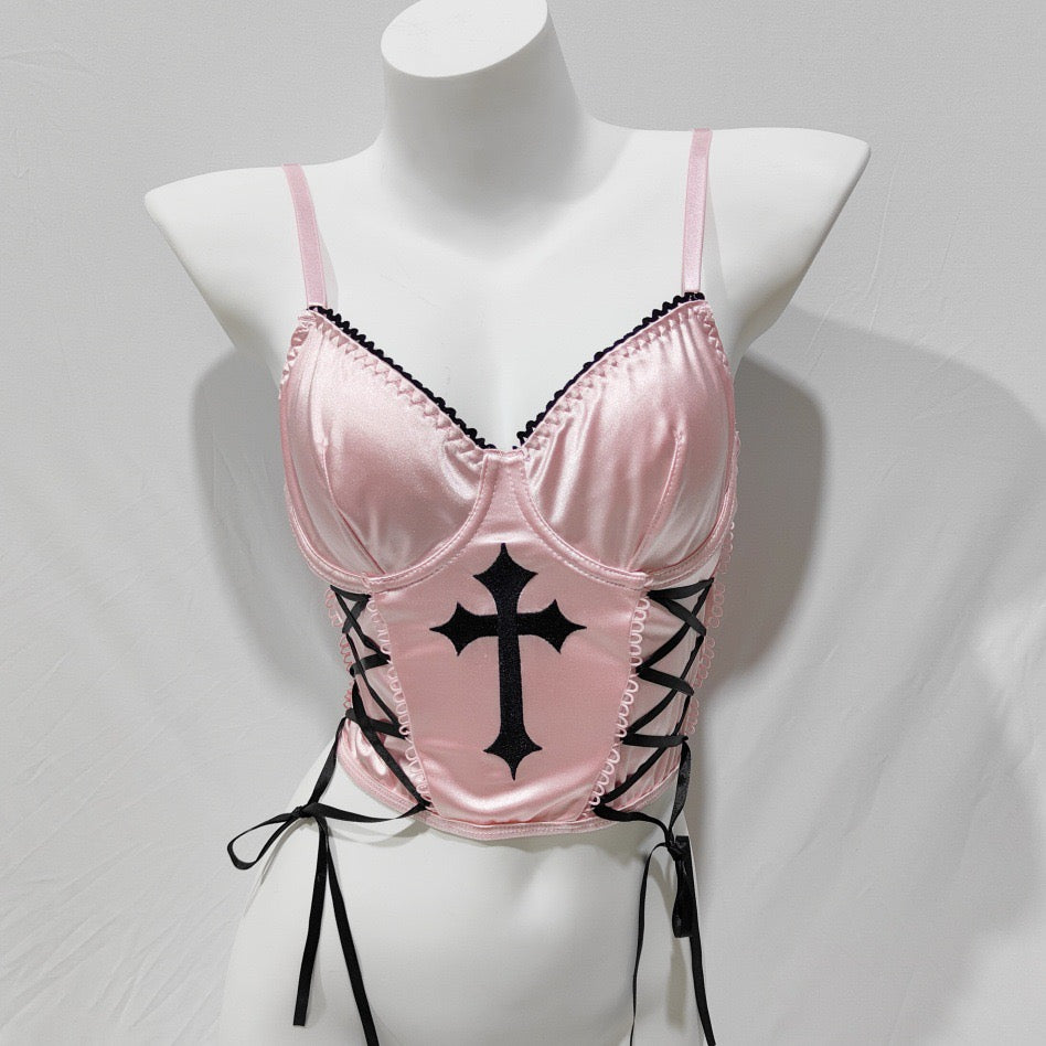 Pink satin lingerie with black cross design on a mannequin against a gray background