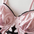 Close-up of a pink bra with black lace trim and star designs.