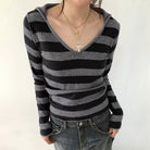 Person wearing a black and gray striped hoodie with a plain background
