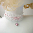 Lace choker with pink ribbons and a heart-shaped pendant on a mannequin.