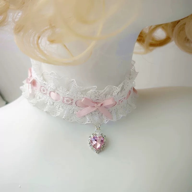 Lace choker with pink ribbons and a heart-shaped pendant on a mannequin.