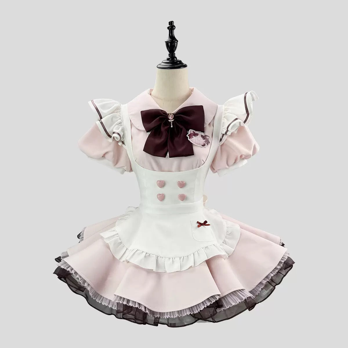 Pink and white dress with a large brown bow on a mannequin against a light gray background