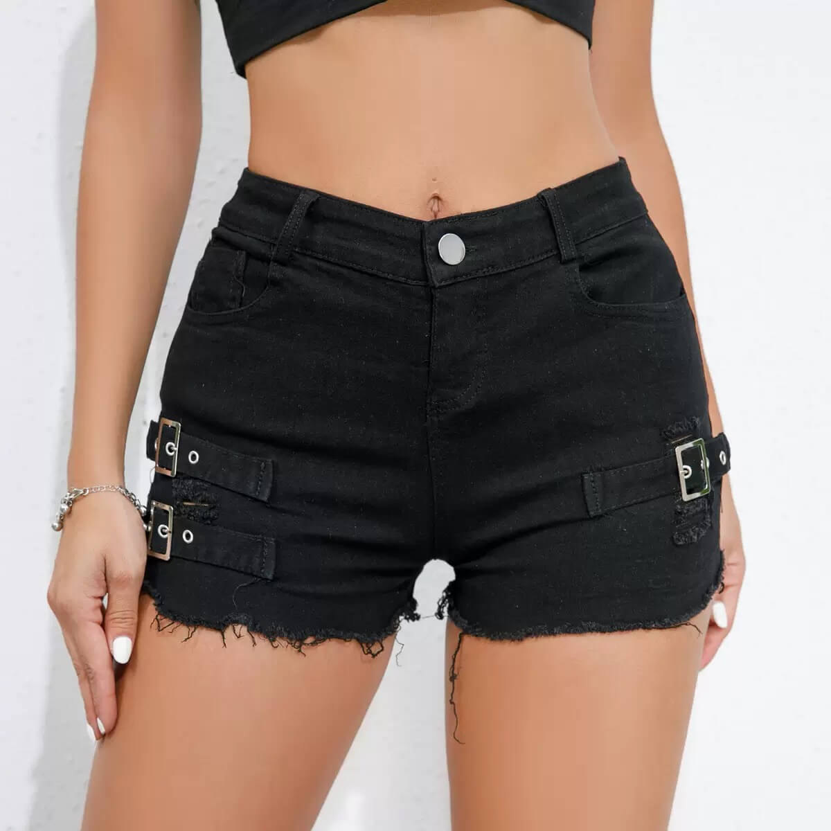 Black denim shorts with metal buckles worn by a person on a white background