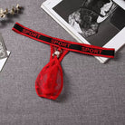 Red garter belt with mesh pouch and pearl charm on a gray surface.