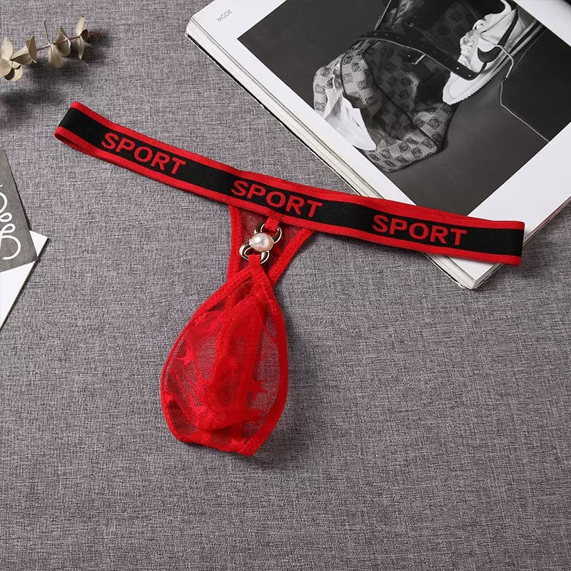 Red garter belt with mesh pouch and pearl charm on a gray surface.