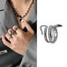 Silver snake-shaped rings on a hand with a necklace, displayed against a white background.